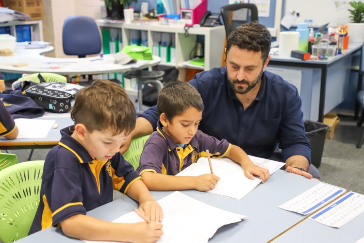 Teacher working with 2 Stage 1 students who are writing