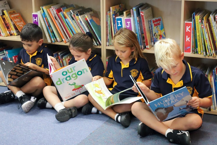 4 Kindergarten students reading picture books in the library