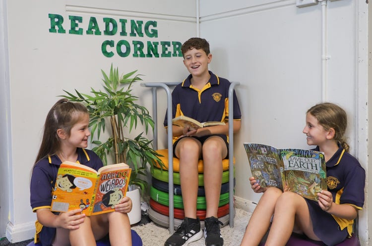 3 Stage 2 students reading books in the classroom reading corner