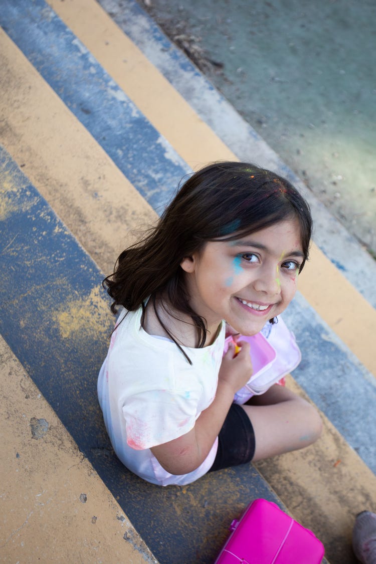 Stage 1 student sitting on the outdoor steps, after completing the colour run