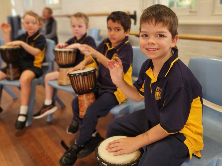 stage 1 boy playing a drum with his classmates