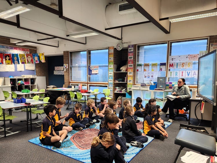 A Stage 1 classroom with the teacher sitting in front of the class